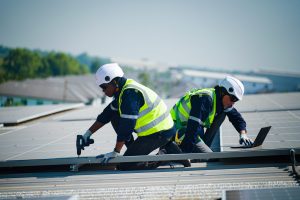 engineers installing solar panels on roof. Male engineers walking along rows of photovoltaic panels